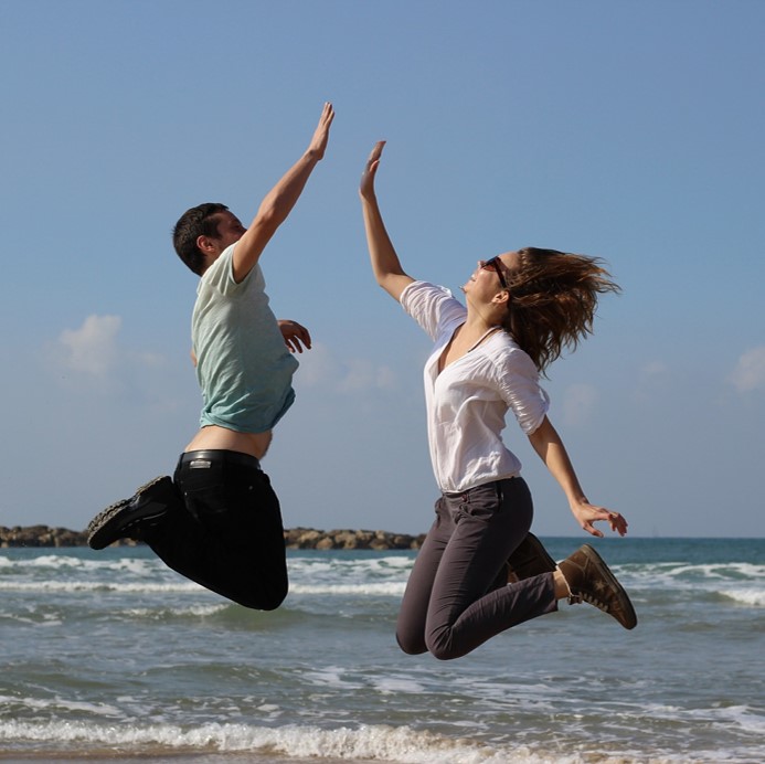 Bild på två personer som hoppar och gör en high five